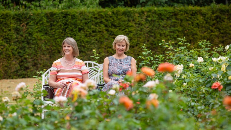 Visitors sat on a bench in the Rose Garden in July at Cliveden, Buckinghamshire